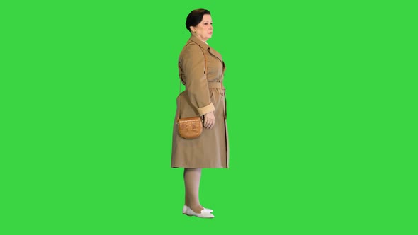 Middleaged Woman in Trench Standing on a Green Screen Chroma Key