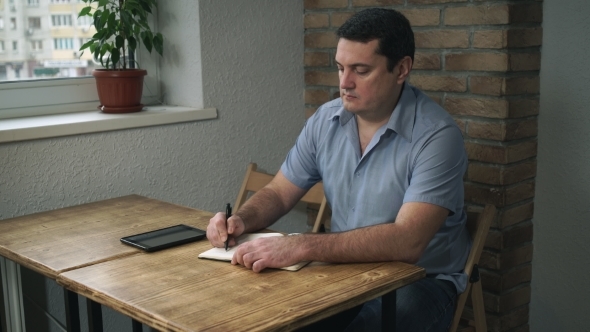 Adult Male Sitting In a Cafe With a Diary