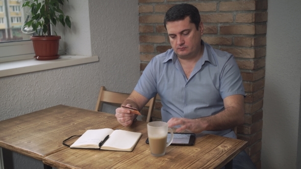 Middle-aged Man Pays Bills Over The Internet In The Hands Of The Credit Card. alt