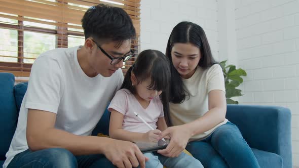 Happy asian family father mother and kid daughter sitting and using computer laptop technology