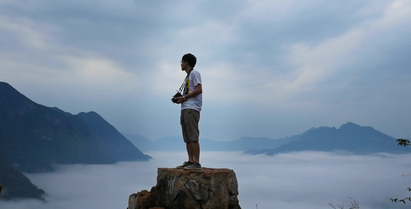 Man With Camera Standing at The Top of Mountain 