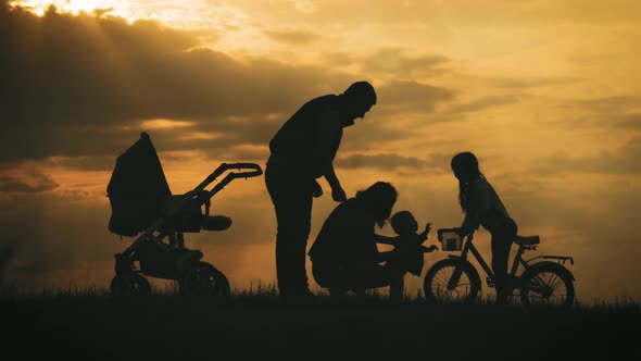 Silhouettes of Happy Parents Having Good Time with Their Little Children on Park