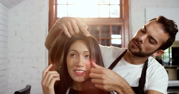 Male hairdresser styling a womans hair