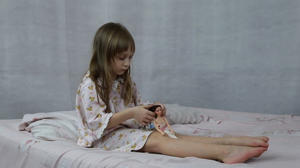 Girl Playing with Doll Sitting on the Bed