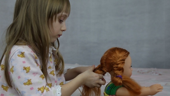 Girl Playing with Doll Sitting on the Bed