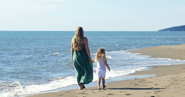 Mother And Daughter Walking On The Beach 