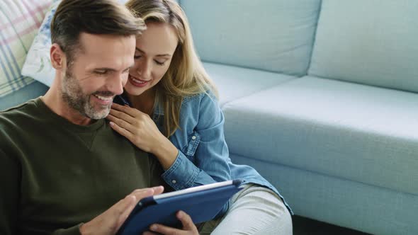 Mature couple using tablet in living room