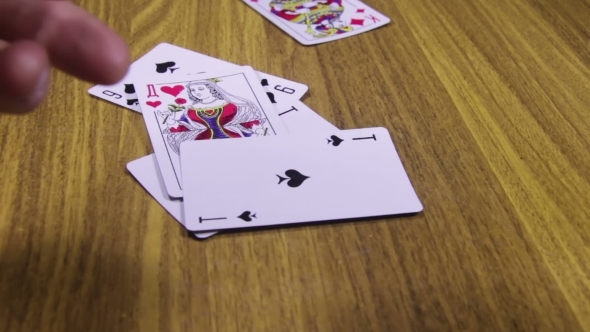 Playing Cards Rotates On a Wooden Table alt