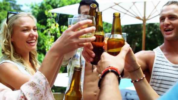 Group of happy friends toasting beer bottles and glasses at outdoors barbecue party