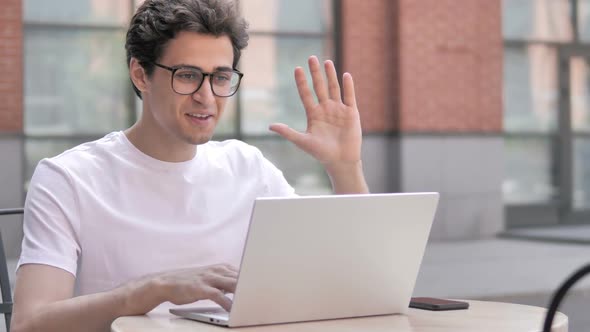 Online Video Chat on Laptop By Young Man Sitting Outdoor