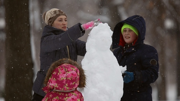 Happy Family Sculpts Snowman Out of Snow