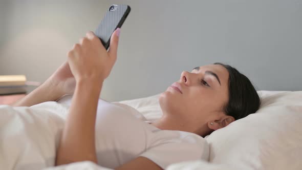 Smartphone Use By Latin Woman Laying in Bed 