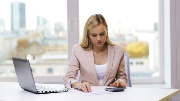 Businesswoman With Laptop, Calculator And Papers