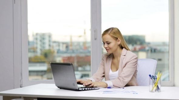 Smiling Businesswoman With Laptop And Papers