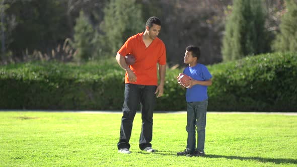 A father teaching his sons how to play American football.