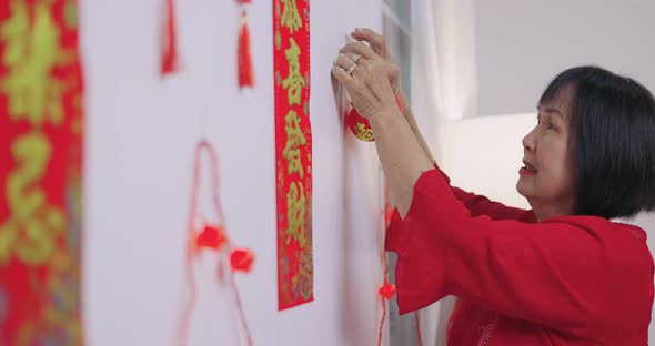 Asian Senior Woman Decorate Her House For Chinese New Year Celebrations.