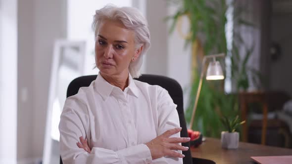 Confident Proud Mature Woman Crossing Hands in Slow Motion Looking at Camera Sitting in Office