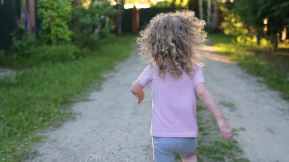 child runs forward towards adventure. A little girl runs away from the camera