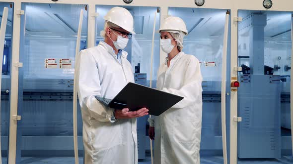 Two Inspectors in Face Masks are Talking Near Modern Plant Machines