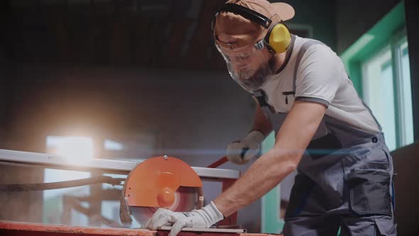 Ceramic Worker Using Electric Tile Cutter in Construction Studio