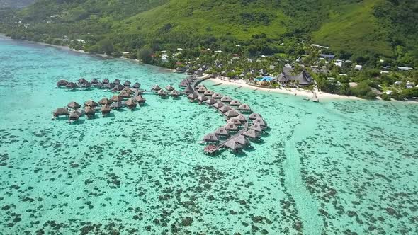 drone luxury overwater bungalow resort fly over of coral reefs and turquoise water