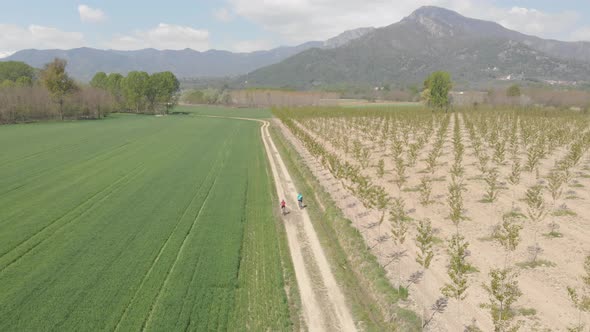 Couple having fun by riding mountain bike on dirt road in sunny day, scenic landscape of snowcapped