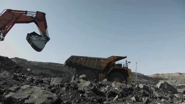 Giant Dump Truck is Reversing Towards an Excavator