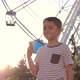 Authentic a boy eats ice cream in the park against the background of a Ferris wheel. - VideoHive Item for Sale