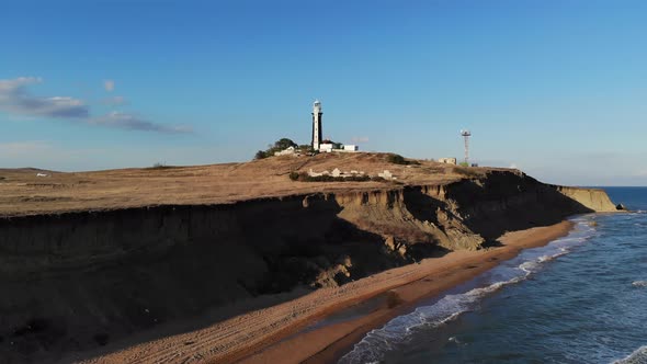 Aerial View of an Unknown Lighthouse with Black and White Edges on the Peninsula's Promontory