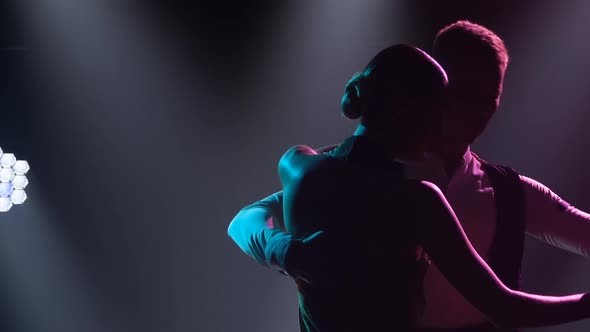 Couple is Dancing Fast Rhythmic Tango Dance in Dark Studio with Bright Spotlights