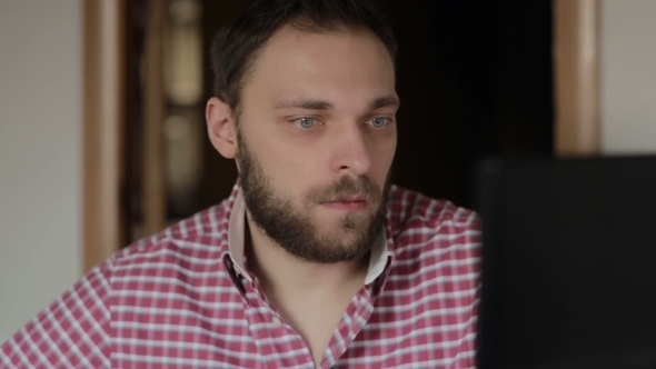 Serious Man Working At a Computer In a Home Office
