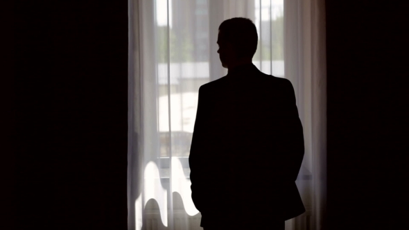 Silhouette Of Stylish Man In Suit Looking Out The Window
