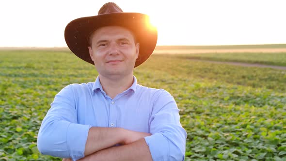 Portrait of a Young Farmer in a Blue Shirt and Hat and Looking at the Camera at Sunset