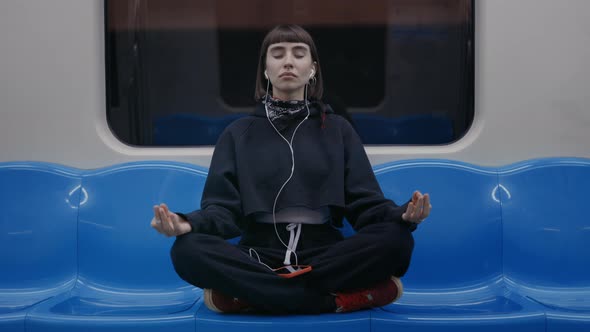 Woman Sitting in Lotus Position at Subway and Meditating