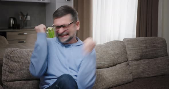 Mature Man Celebrating Success on Sofa