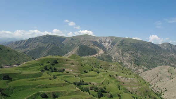 Green hilly landscape on blue cloudy sky background