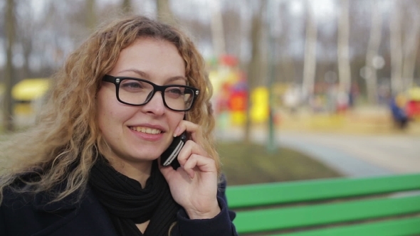 Young Woman Talking On The Phone Outdoors In a Park