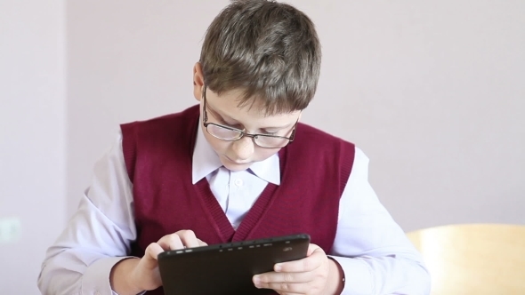 Boy With Glasses Playing The Tablet At School