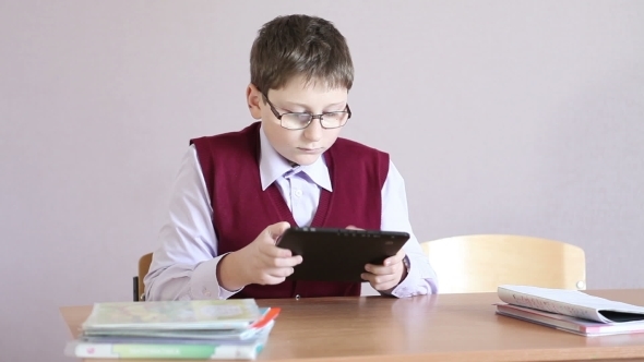 Boy With Glasses Playing The Tablet At School