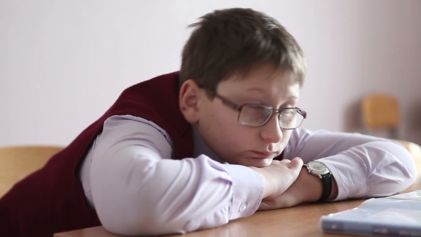 Sad Boy With Glasses Sitting In a Classroom