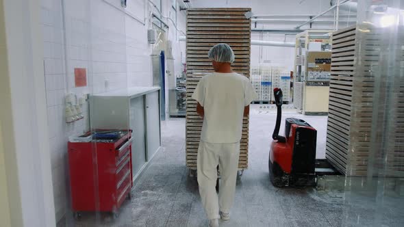 Factory Worker Pushing Cart with Candies in Storage Room.