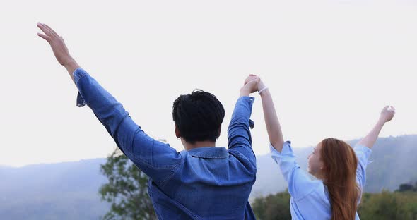 Romantic Asian couple walking and holding hands together on mountain background.