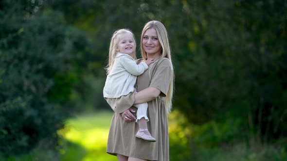 Happy young mum and baby walking together outdoor enjoy beautiful field of sunshine