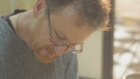 Man in Glasses is Sculpting a Head Fixing a Nose