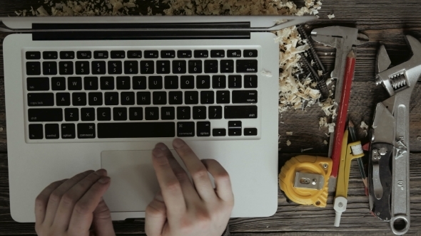 Carpenter Using Laptop Computer on Wooden Table alt