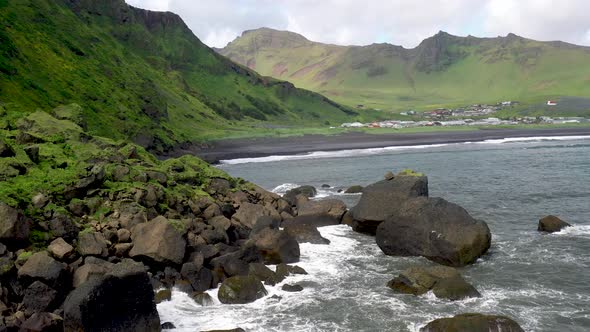 Vik, Iceland coast with waves crashing on rocks with drone video moving forward.