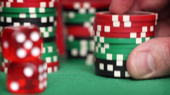 Red Dice And Casino Chips In Fingers On Green Table