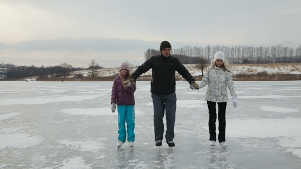 Father With Daughters Ice Skating On Frozen Lake