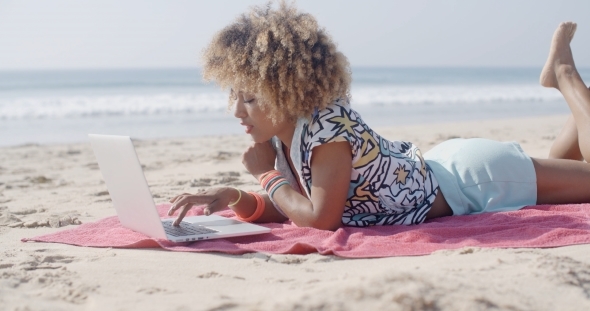 Woman On The Beach Using A Computer
