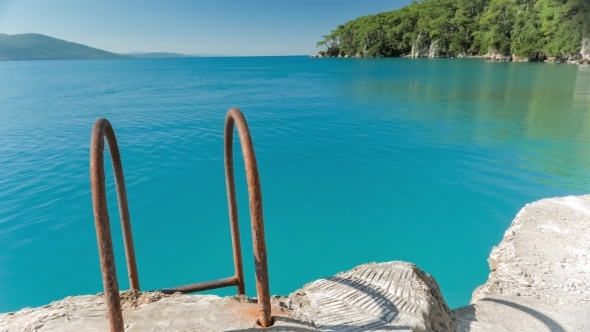 Metal Rusty Ladder With Handrails At a Stone Pier